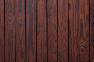 Close-up texture detail of vertical charredwoodcanada ltd reddish-brown Thermo Pinus Radiata charred wood cladding boards, featuring a brushed surface that highlights the natural wood knots, deep grain, and dark crackled Yakisugi charring patterns.