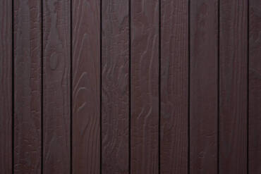 Close-up texture detail of vertical charredwoodcanada ltd dark brown Thermo Pinus Radiata charred wood cladding boards, featuring a brushed surface that highlights the wood grain and crackled Shou Sugi Ban charring patterns.