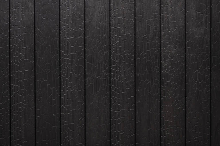 Close-up texture detail of vertical charredwoodcanada ltd deep black charred wood cladding boards, featuring a heavily charred surface with a distinctive crackled Yakisugi pattern.