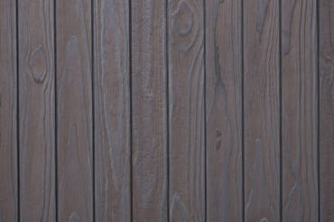 Close-up texture detail of vertical charredwoodcanada ltd light grey Thermo Pinus Radiata charred wood cladding boards, featuring a brushed surface that highlights the raised wood knots, deep grain textures, and dark Yakisugi charring.