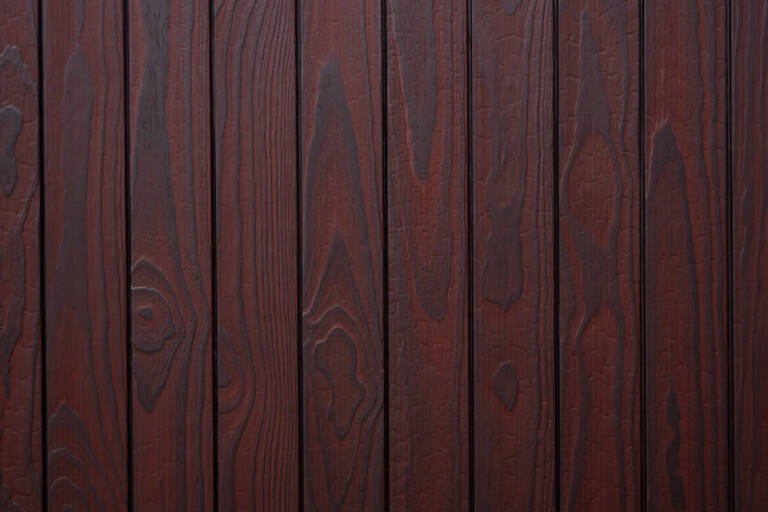 Close-up texture detail of vertical charredwoodcanada ltd reddish-brown Thermo Pinus Radiata charred wood cladding boards, displaying a brushed surface that emphasizes the raised wood grain, knots, and dark Shou Sugi Ban charring patterns.